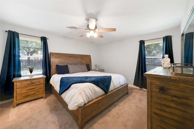 bedroom featuring light carpet, multiple windows, and ceiling fan