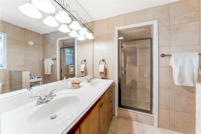 bathroom with tile patterned flooring, vanity, a shower with door, and tile walls