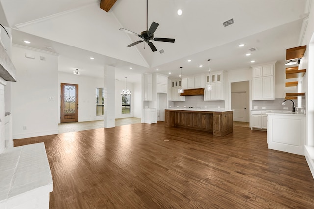 unfurnished living room with dark wood-type flooring, high vaulted ceiling, beamed ceiling, and ceiling fan with notable chandelier