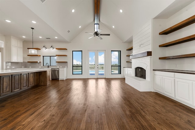 unfurnished living room with a fireplace, dark hardwood / wood-style floors, high vaulted ceiling, and ceiling fan