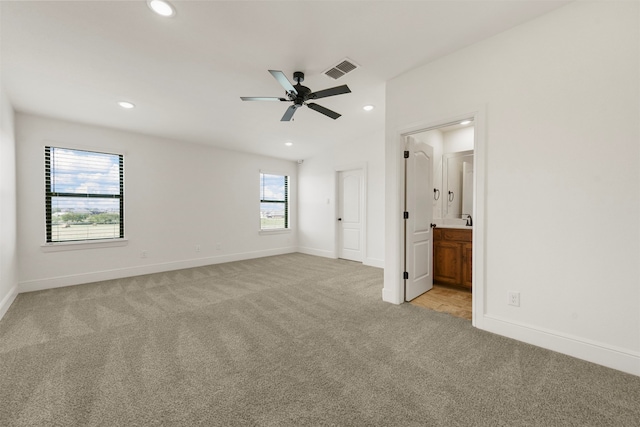 unfurnished bedroom featuring light carpet, connected bathroom, and ceiling fan