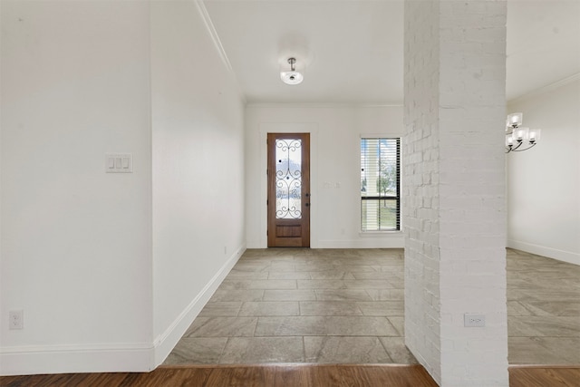 foyer featuring an inviting chandelier, decorative columns, crown molding, and light wood-type flooring