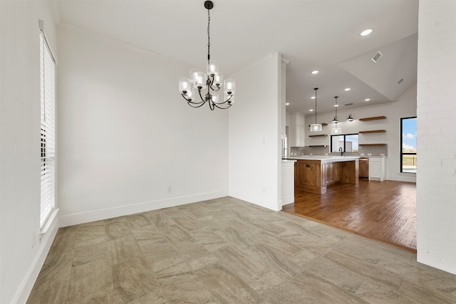 interior space featuring an inviting chandelier, ornamental molding, light wood-type flooring, and vaulted ceiling