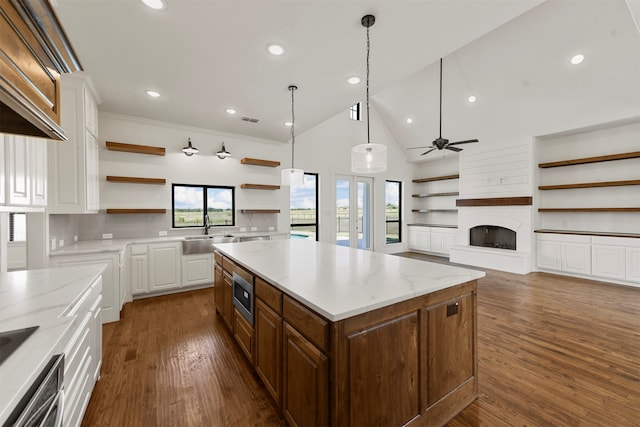 kitchen with stainless steel microwave, a wealth of natural light, a kitchen island, and white cabinets