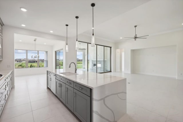 kitchen with gray cabinets, a kitchen island with sink, decorative light fixtures, sink, and light stone countertops