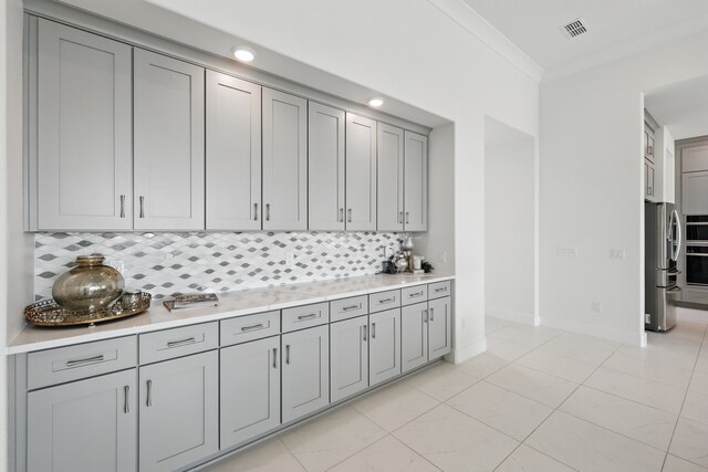 kitchen with gray cabinetry, tasteful backsplash, appliances with stainless steel finishes, and baseboards