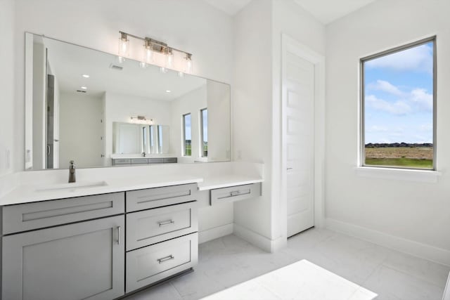 bathroom with marble finish floor, vanity, and baseboards