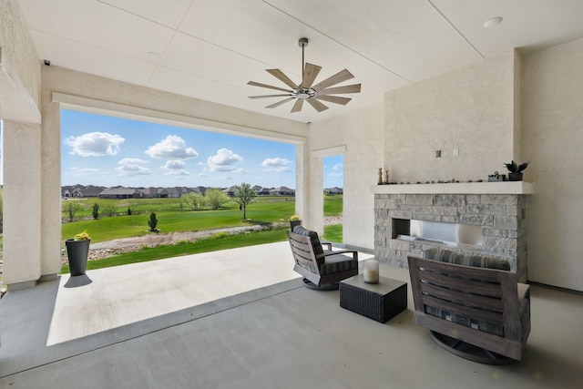 view of patio with an outdoor stone fireplace, a ceiling fan, and view of golf course