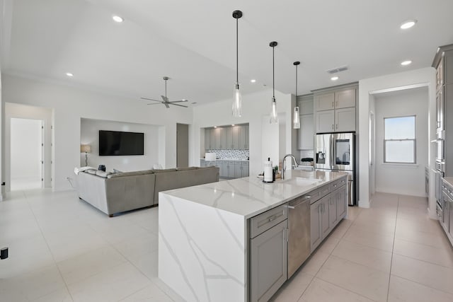 kitchen with a sink, visible vents, light stone counters, gray cabinetry, and appliances with stainless steel finishes