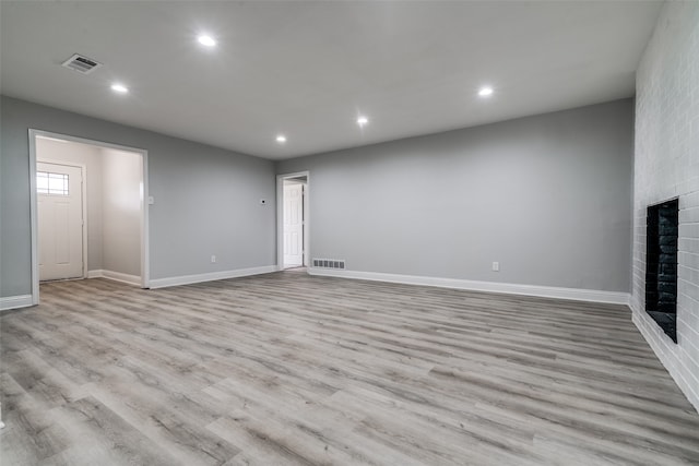 unfurnished living room featuring a fireplace and light hardwood / wood-style floors