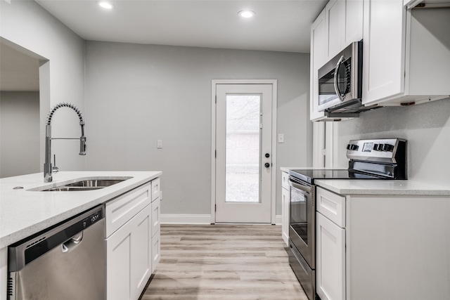 kitchen with light hardwood / wood-style flooring, stainless steel appliances, sink, and white cabinetry