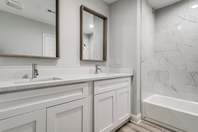 bathroom with tiled shower / bath combo, hardwood / wood-style flooring, and vanity