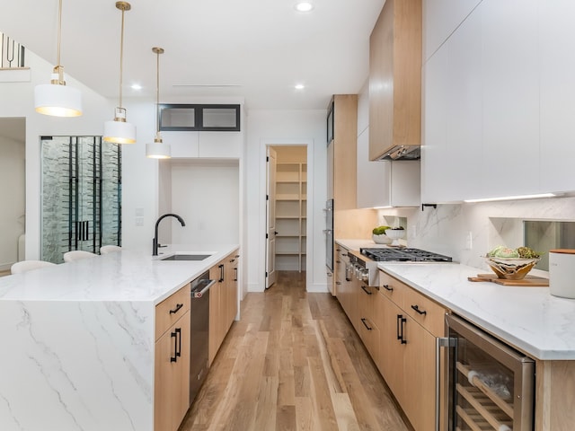 kitchen with light stone counters, decorative light fixtures, light hardwood / wood-style flooring, white cabinets, and wine cooler