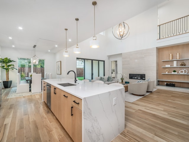 kitchen featuring sink, hanging light fixtures, light stone counters, light hardwood / wood-style flooring, and a spacious island