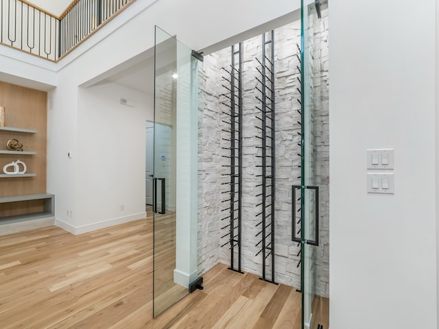 wine cellar with wood-type flooring and a towering ceiling