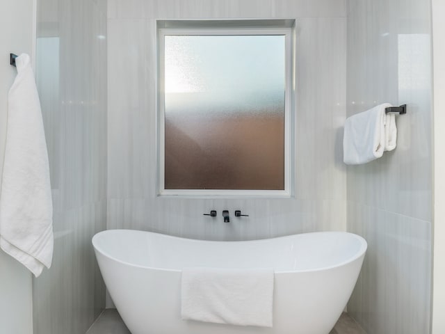 bathroom featuring a washtub and tile walls