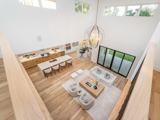 living room with hardwood / wood-style floors, a chandelier, a high ceiling, and sink