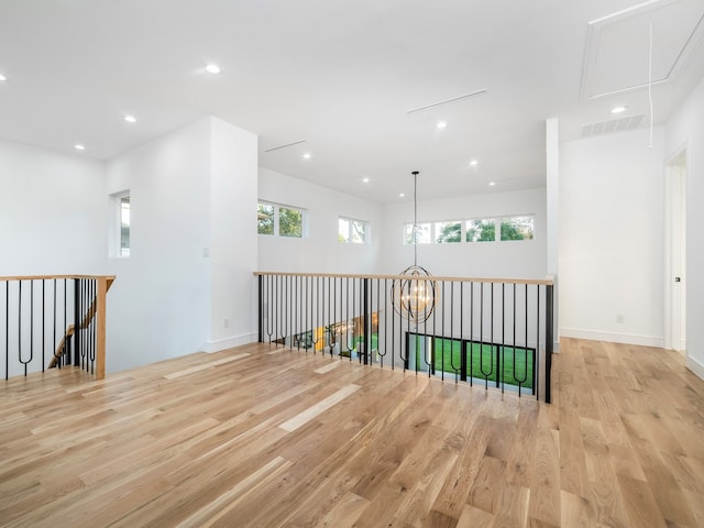 hallway featuring an inviting chandelier, a healthy amount of sunlight, and light hardwood / wood-style floors