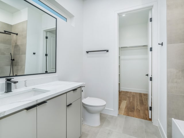 bathroom featuring hardwood / wood-style floors, vanity, toilet, and tiled shower