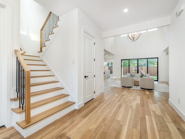 stairway featuring a high ceiling, hardwood / wood-style flooring, and a notable chandelier