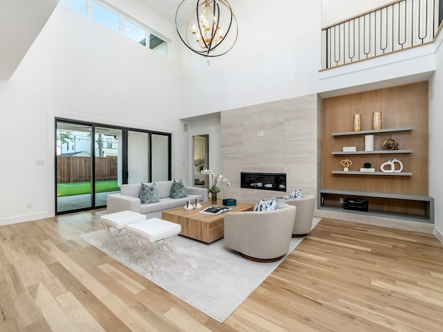 living room featuring a healthy amount of sunlight, a towering ceiling, a fireplace, and light hardwood / wood-style flooring