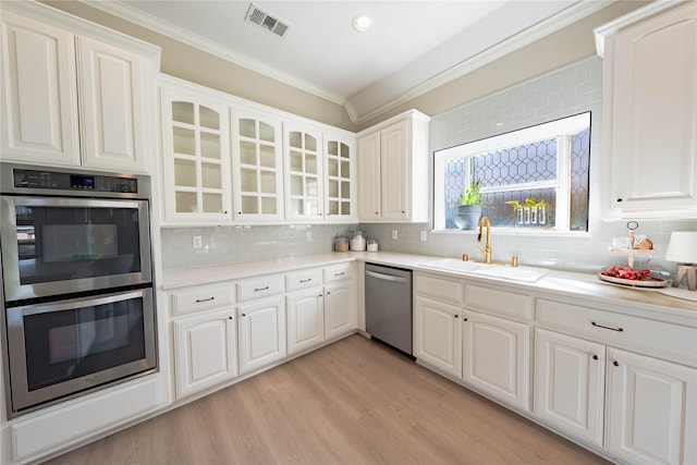 kitchen with glass insert cabinets, a sink, visible vents, stainless steel appliances, and ornamental molding