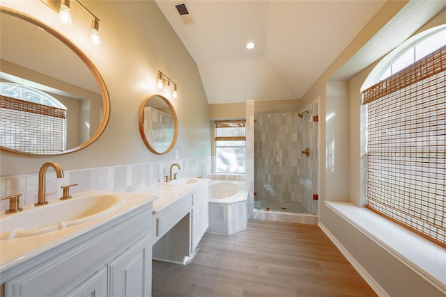 full bath with lofted ceiling, a garden tub, wood finished floors, vanity, and tiled shower