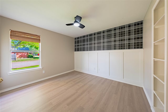 empty room featuring a ceiling fan, light wood-style flooring, and baseboards