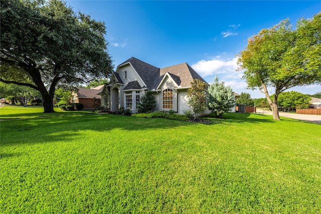 view of front of home with a front yard and a shingled roof