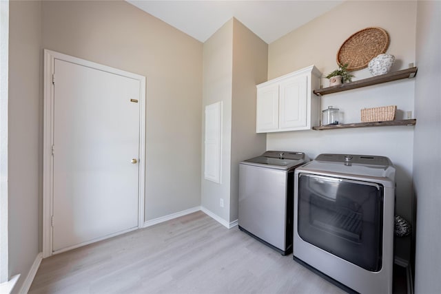 washroom featuring washing machine and dryer, cabinet space, baseboards, and light wood-style floors