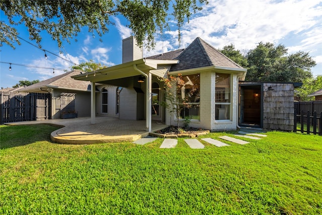 rear view of house with a patio, fence, a chimney, and a yard