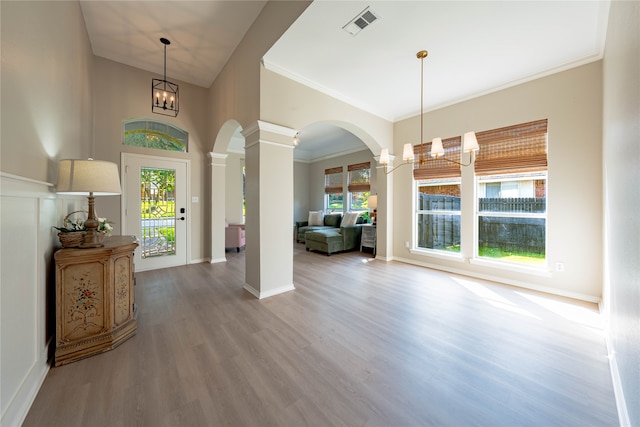 entrance foyer with ornamental molding, decorative columns, a notable chandelier, and hardwood / wood-style floors