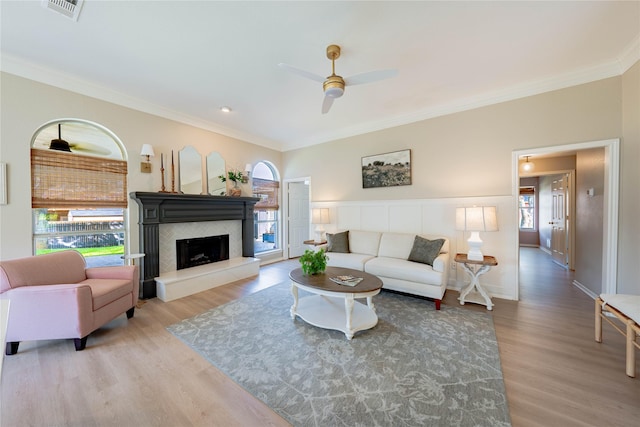 living area with wood finished floors, visible vents, crown molding, and a ceiling fan