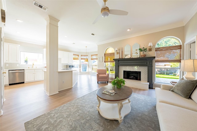 living area with visible vents, light wood-type flooring, plenty of natural light, and crown molding
