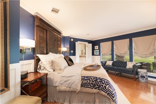 bedroom with wood-type flooring, connected bathroom, and ornamental molding