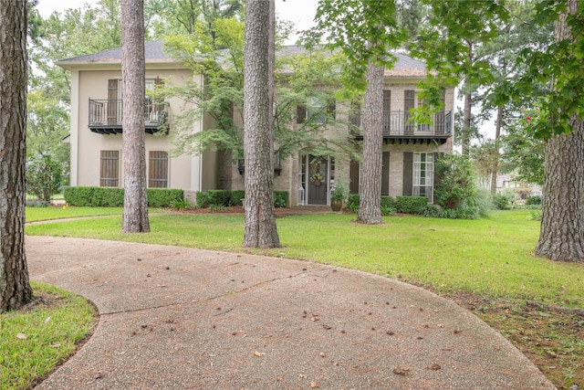 view of front facade with a front lawn and a balcony