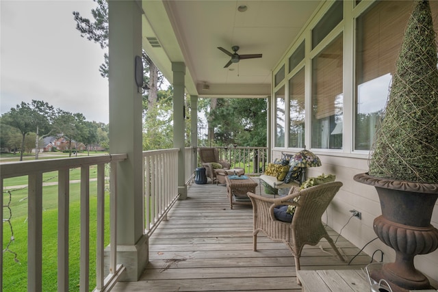 wooden terrace with ceiling fan, a porch, and a lawn