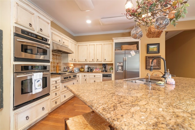 kitchen with light hardwood / wood-style flooring, sink, light stone counters, stainless steel appliances, and a kitchen bar