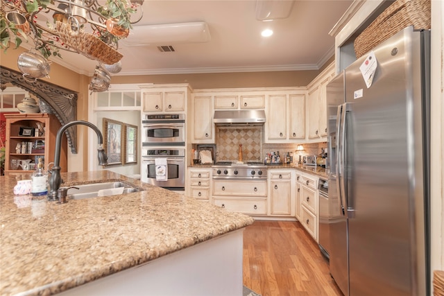 kitchen featuring light wood-type flooring, light stone counters, stainless steel appliances, sink, and ornamental molding