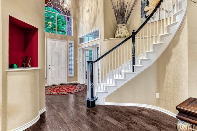 entrance foyer featuring a towering ceiling, hardwood / wood-style flooring, a healthy amount of sunlight, and a notable chandelier