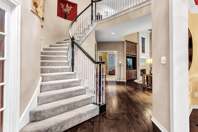 staircase featuring wood-type flooring and a towering ceiling