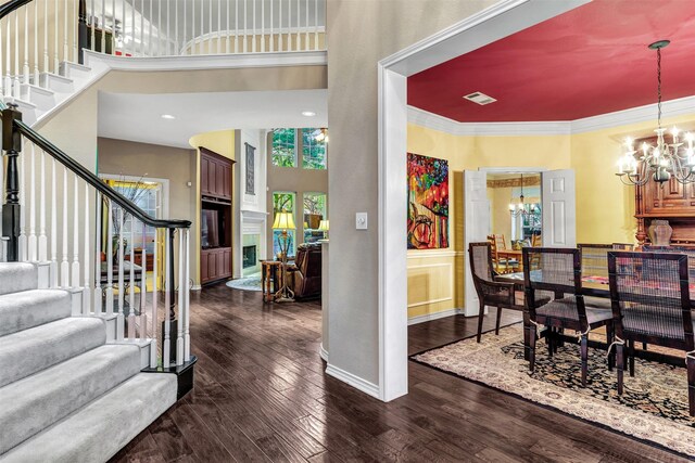 interior space with dark hardwood / wood-style floors, ornamental molding, a towering ceiling, and an inviting chandelier