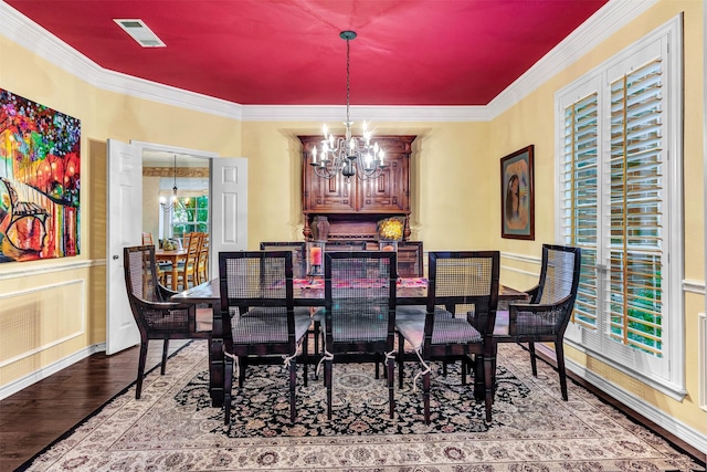 dining space with a notable chandelier, crown molding, and light hardwood / wood-style flooring