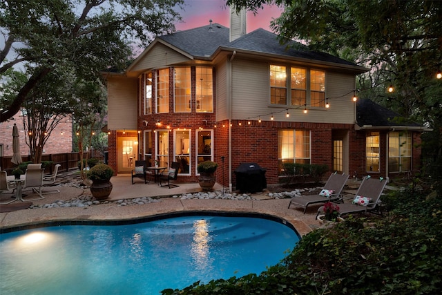 back house at dusk featuring a patio area