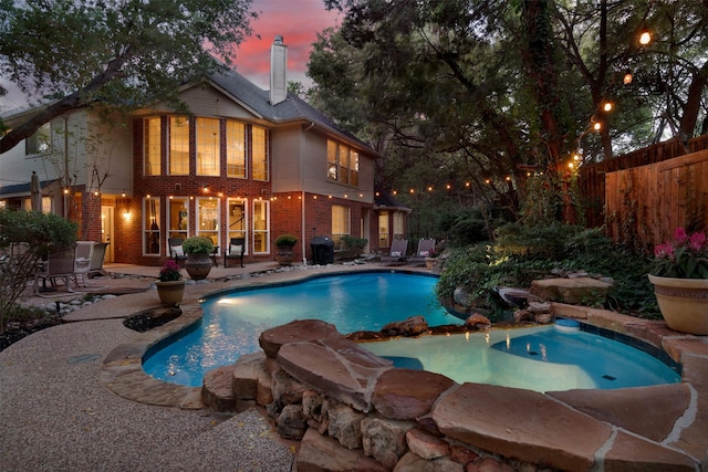 pool at dusk with a grill and a patio area