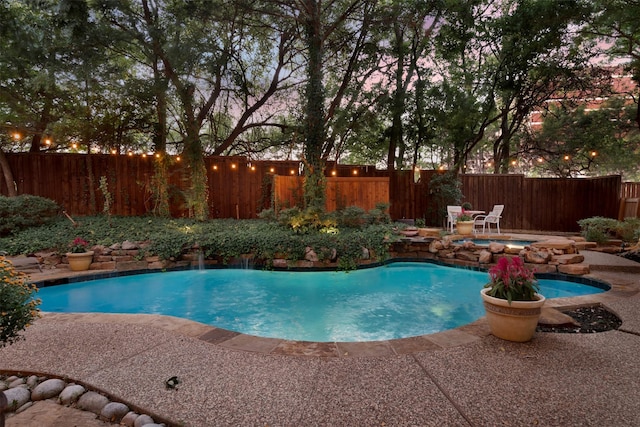 pool at dusk with a patio area