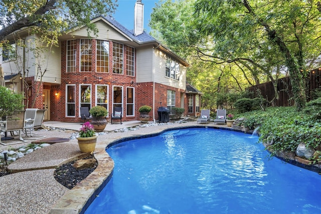 view of swimming pool with a grill, pool water feature, and a patio