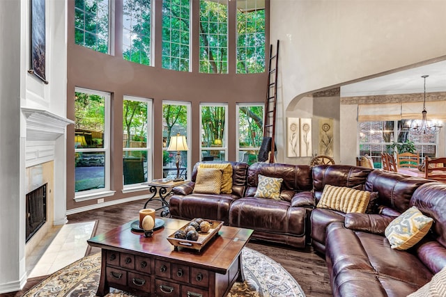 living room featuring a fireplace, a high ceiling, and an inviting chandelier