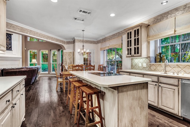 kitchen with hanging light fixtures, stainless steel dishwasher, dark hardwood / wood-style floors, ornamental molding, and a kitchen island