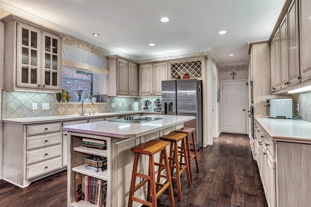 kitchen featuring a kitchen bar, stainless steel refrigerator with ice dispenser, a center island, and ornamental molding